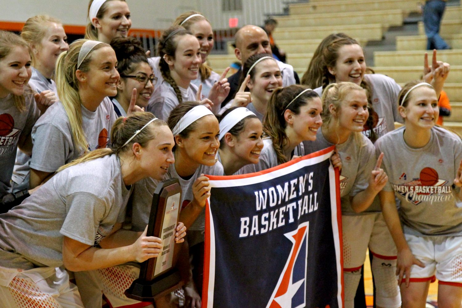 The Baker womens basketball players pose for a photo with their Heart championship banner after defeating Benedictine 64-51. The team won its first-ever Heart Conference Tournament title along with the regular-season championship. Photo by Chad Phillips.