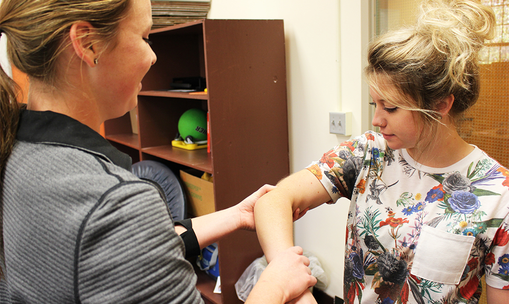 Sophomore Sierra McKinney palpates the arm muscle of sophomore Baylee Bartgis. McKinney and Bartgis are both exercise science majors. Image by Elizabeth Hanson.