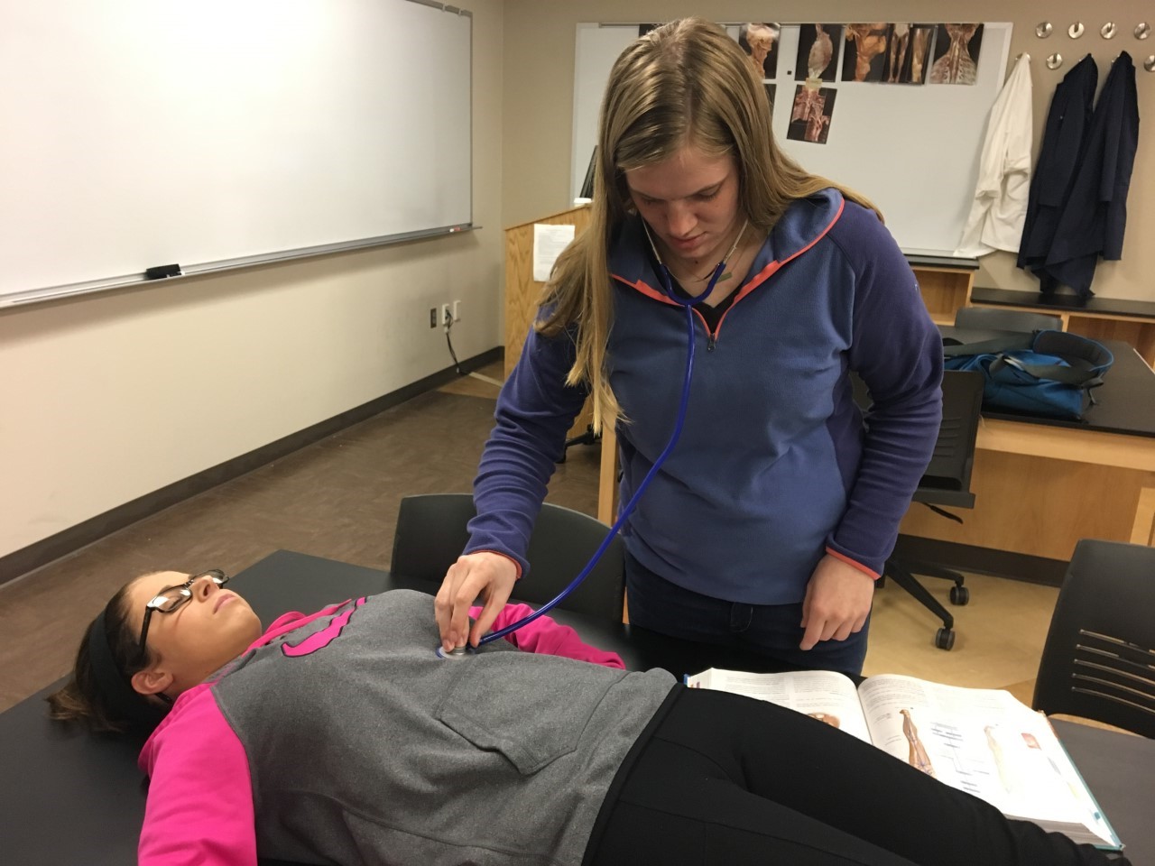 Sophomore Allyson Fry listens to sophomore Mikayla Ladys abdominal sounds during Anatomy and Physiology lab.