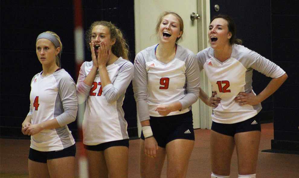 Freshmen Megan Milroy and Morgan Thomas, senior Michelle Tennant, and junior Gabby Miller laugh and cheer together from the sidelines. The game took place in the Collins Center on Sept. 26.