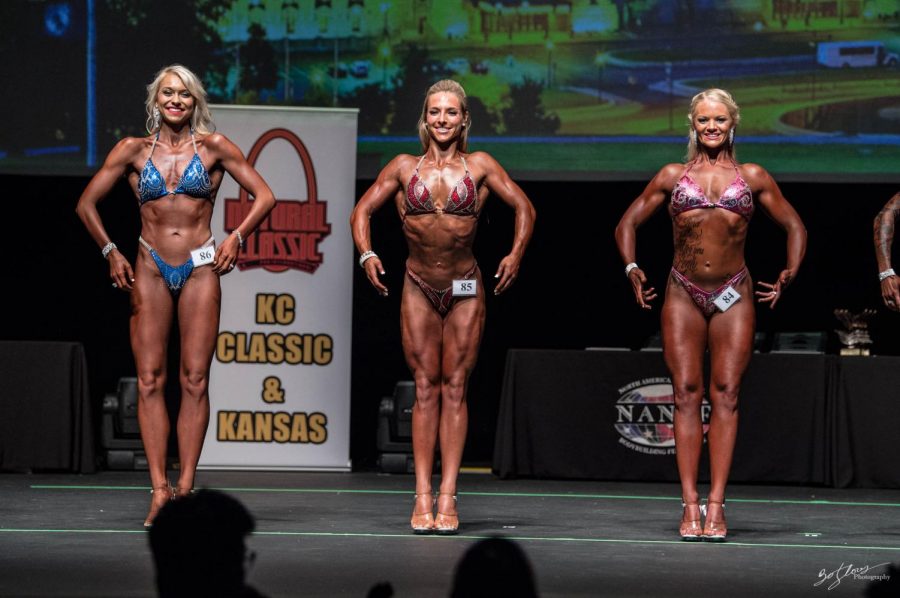 Swickard (middle) stands on stage displaying her figure to the judges and crowd. 