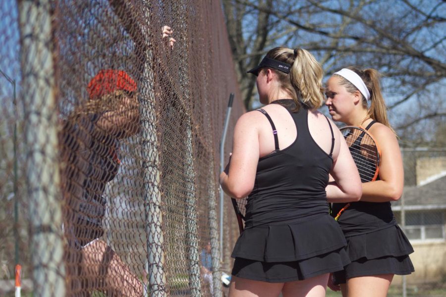 Bakers No. 2 doubles team of senior Holly Chestnut and junior Sophie Robertson talk with assistant coach Lexi Hertling between games on Monday. The doubles team picked up a win over Missouri Valley College 8-5