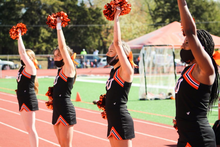 Members of the cheer team performing on the sidelines during the game. 