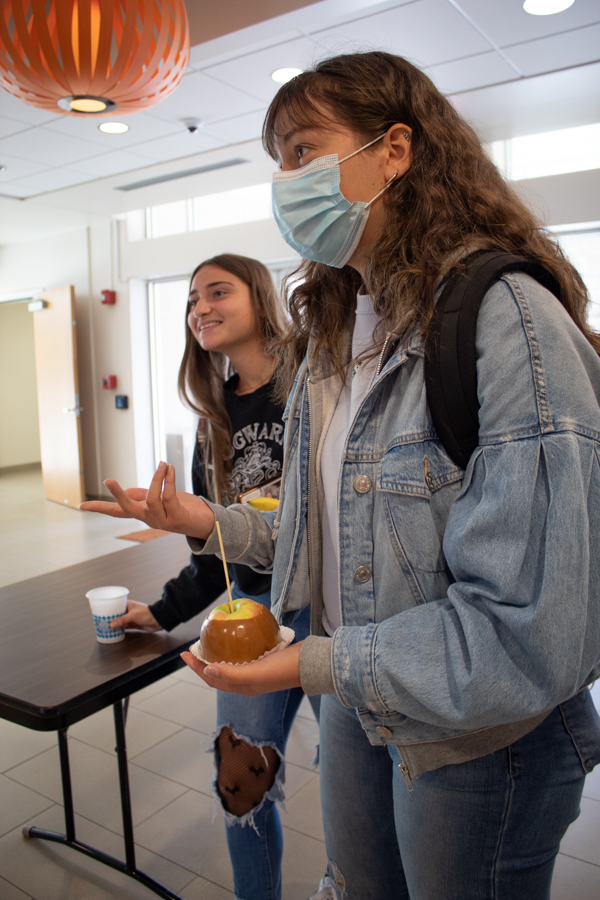 Freshmen Bea Weinpel and Ciarra McWilliams enjoy their caramel apples and apple cider while talking with friends in the Union.