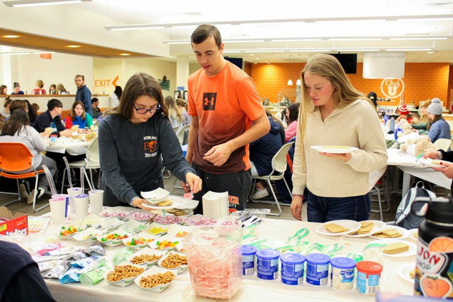 Sophomore Kinsey Miller and Freshmen Tanner McGuire and Nicole Merical get in line to get their materials for their gingerbread houses.