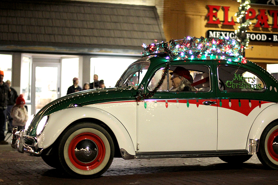 As part of the Festival of Lights parade, a vintage car rolls down Eighth St. 