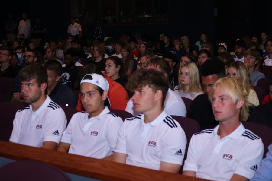Mens soccer players sit with one another in uniform. Other teams on campus sat along side each other. 