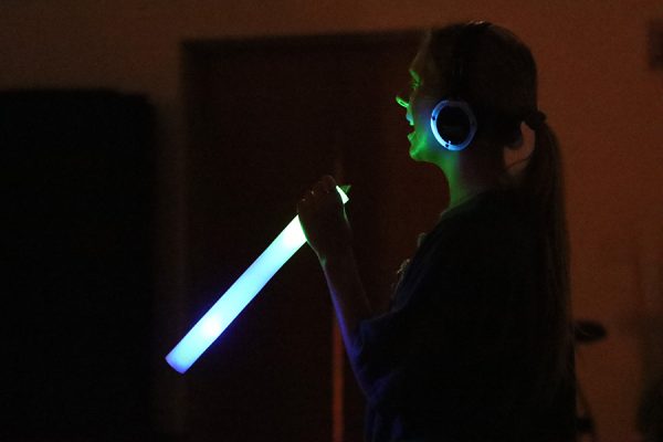 A student uses her glow wand as a makeshift microphone at headphone disco on April 25. 