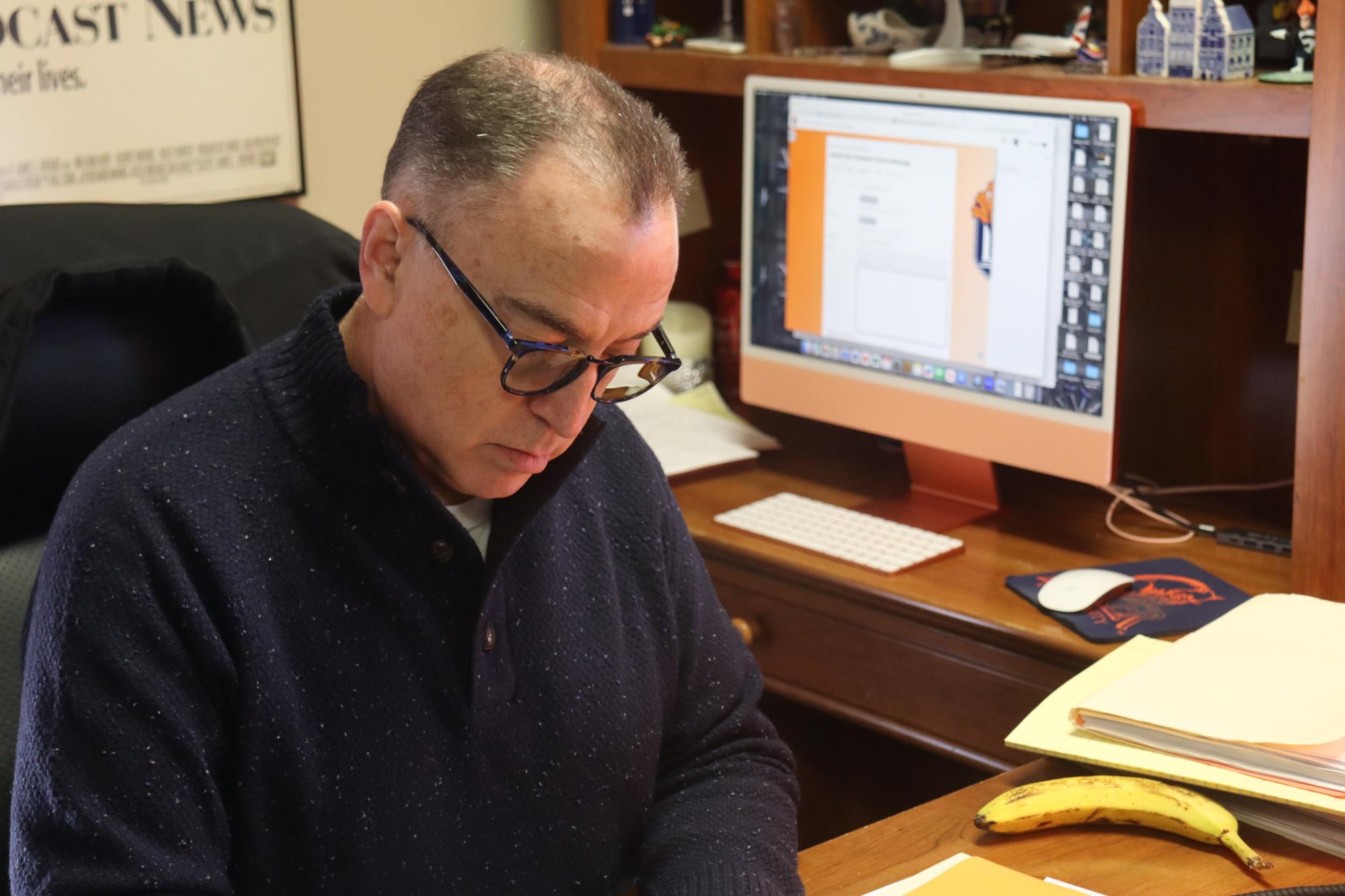 Dr. Joe Watson sits at his desks grading papers from one of his classes.