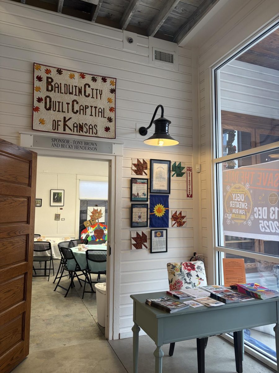 Immediately after entering the Lumberyard Arts Center, in the right corner, hangs a quilt recognizing Baldwin City as the Quilt Capital of Kansas alongside the resolution that made it happen and information about upcoming events at the LAC.