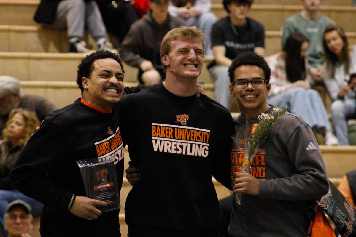 Wrestlers Jazen Brown, Hunter Hall and Eli Kennedy smiling for the cameras after Hall receives his senior recogntion.